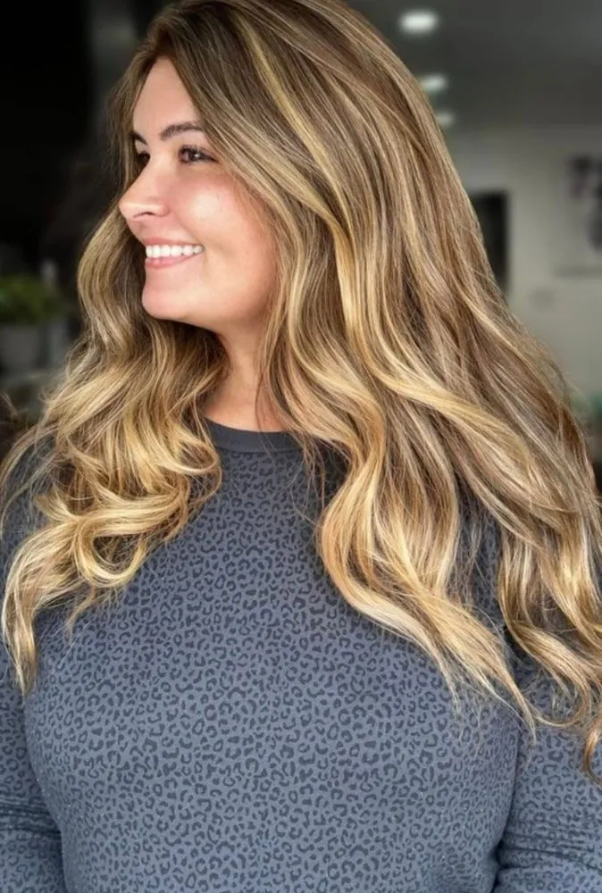A warm, smiling client with a soft blonde balayage — the kind of finish Valla creates one client at a time at The Beauty Suite.