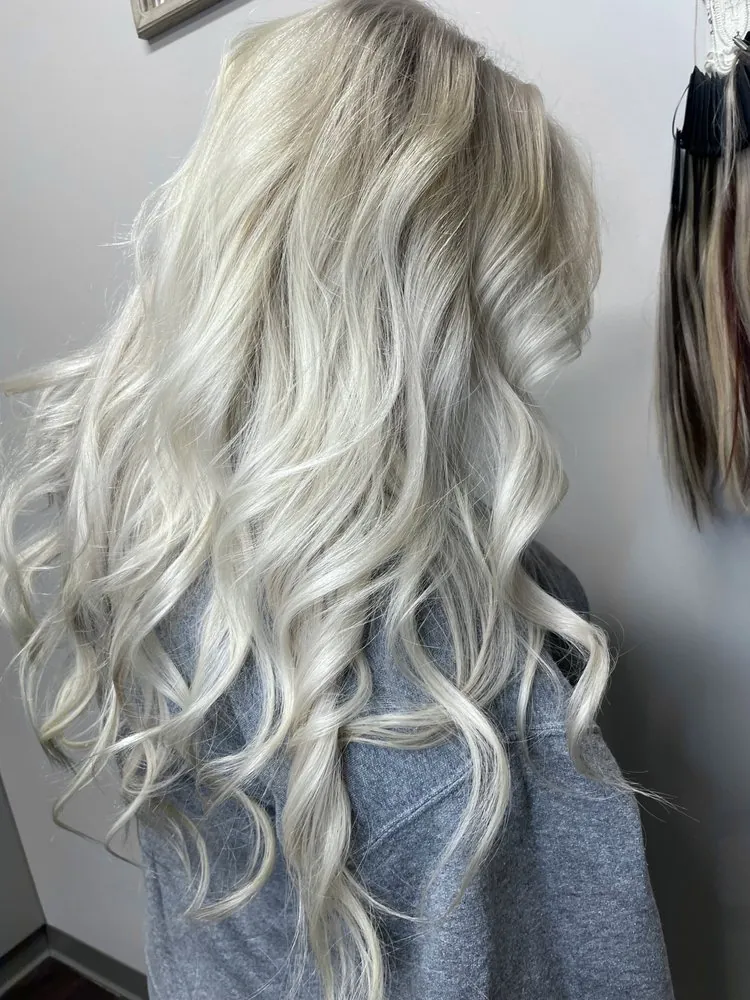 A real color result by Valla — dark hair lifted to a bright icy platinum with dimensional waves.